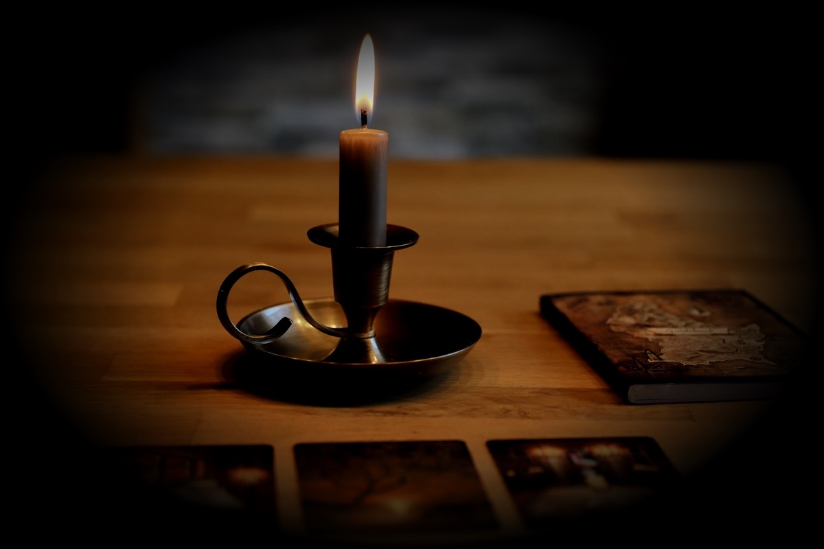 Un bougeoir, des cartes de tarot et un livre ancien sur une table