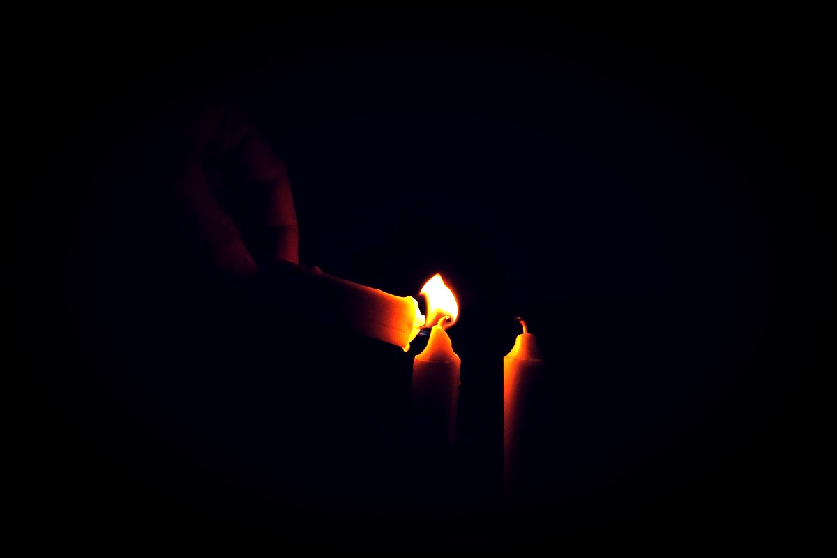 Une main allume des bougies dans le noir