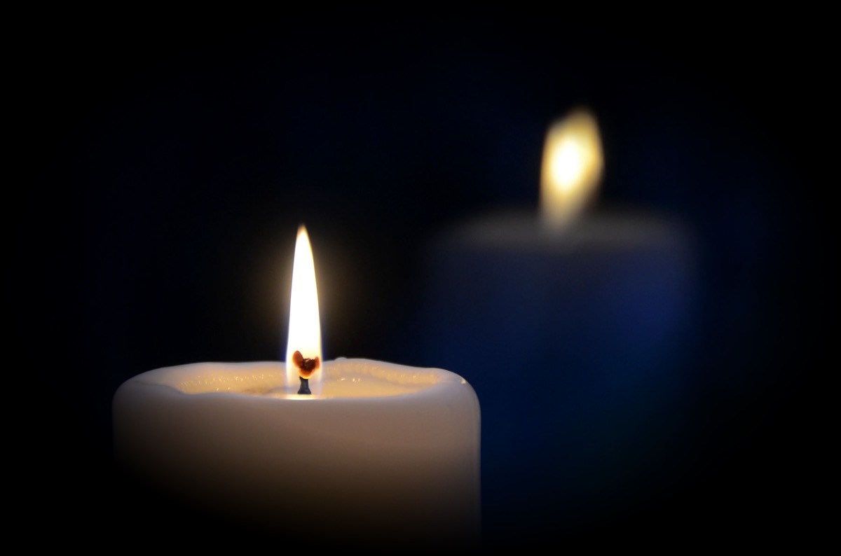 La flamme d'une bougie blanche dans la pénombre