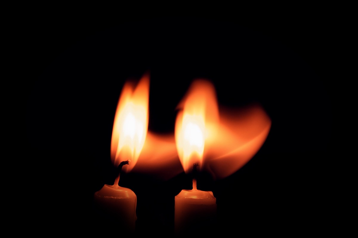 Deux flammes de bougie côte à côte dans l'obscurité