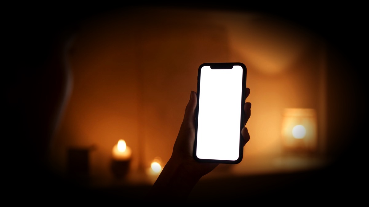 Un téléphone allumé entre des bougies, le soir